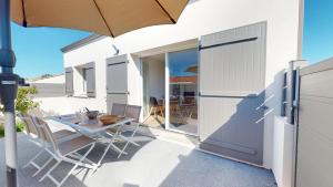 Un patio con una mesa y sillas y una sombrilla. en La Petite Vague, en Saint Gilles Croix de vie