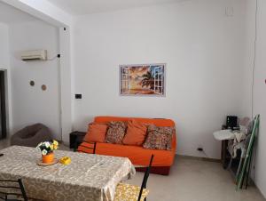 a living room with an orange couch and a table at casa colombo in Balestrate
