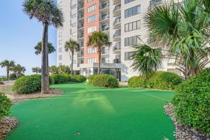a golf course in front of a building with palm trees at Steps to Sand Myrtle Beach Gem with Oceanfront Pool in Myrtle Beach