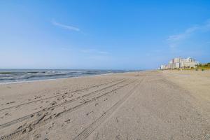 a beach with footprints in the sand and buildings at Steps to Sand Myrtle Beach Gem with Oceanfront Pool in Myrtle Beach