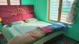 a bedroom with a bed with a pink headboard at River view home stay in Kanzalwan