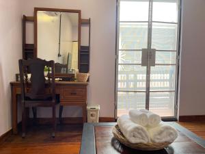 um quarto com uma secretária com um espelho e uma cesta de toalhas em The Memory Hostel em Trat