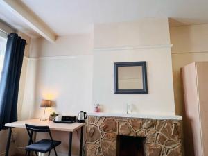 a room with a fireplace with a table and a mirror at Cosy Double Room in Harrow & Wealdstone - Desk,Fast Free Wi-Fi,Near Station - 15 mins by train to Wembley Central & Euston in Harrow Weald