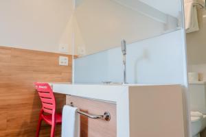 a kitchen with a white counter and a red chair at i5 Hotel - Taguatinga in Taguatinga +4 photos