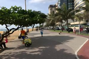 a group of people walking on a sidewalk near the beach at Flat Diamond Beach em Vila Velha in Vila Velha