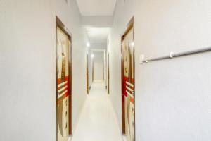 Un pasillo con tres puertas y un largo pasillo con paredes blancas. en Hotel O Srinidhi Inn, en Ameerpet