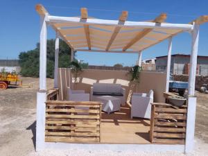 a wooden pergola with a table and chairs on a deck at Villa Ninfa in Lampedusa
