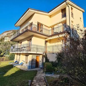a large yellow house with balconies and a yard at Villa Gli Ulivi - Ushuaia Apartment Lake & Garden View - Free Parking in Perledo