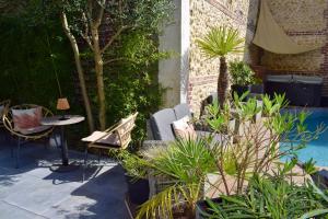a patio with a table and chairs and plants at Le Trophée Boutique Hôtel Spa- La Loggia Appart'hôtel in Deauville
