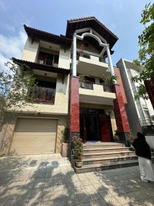 a woman walking past a house with at Cali homestay in Phú Vang