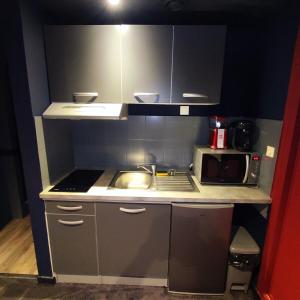 eine kleine Küche mit Spüle und Mikrowelle in der Unterkunft L'évasion popcorn in Saint-Pierre-de-Plesguen