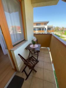 a table and a chair on a balcony with a window at Magnólia Apartmam in Hegykő