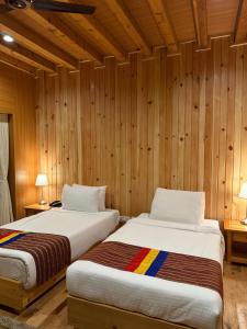 two beds in a room with wooden walls at Spirit of Bhutan resort in Paro