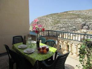 a table with a bowl of fruit and flowers on a balcony at Serenity - Bellevue Gozo in Xlendi