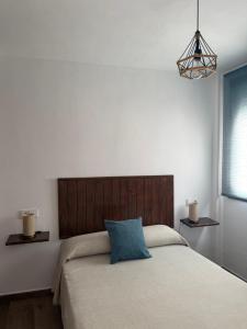 a bedroom with a large bed with a wooden headboard at Apartamentos Bolonia - M a n u e l a in Bolonia