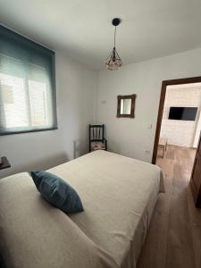 a bedroom with a bed with a blue pillow on it at Apartamentos Bolonia - M a n u e l a in Bolonia