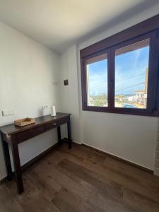 a room with a wooden table and a window at Apartamentos Bolonia - M a n u e l a in Bolonia
