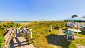 a patio with a table and an umbrella on the beach at Unit 109 -1br Apt Oceanfront Complex With Pool in Cocoa Beach