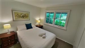 a bedroom with a white bed and two windows at Bellevue - Beautiful View in Mount Victoria