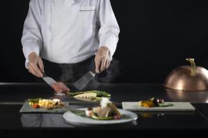 a chef preparing food on a table with plates of food at Courtyard by Marriott Shin-Osaka Station in Osaka