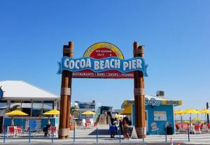 a sign for a beach pier with chairs and umbrellas at Unit 109 -1br Apt Oceanfront Complex With Pool in Cocoa Beach