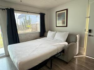 a bed with a chair in a room with a window at Unit 109 -1br Apt Oceanfront Complex With Pool in Cocoa Beach