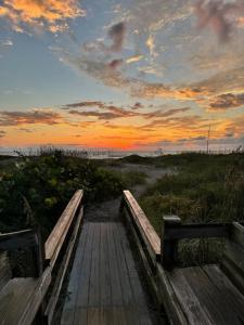 a wooden boardwalk leading to a beach at sunset at Unit 109 -1br Apt Oceanfront Complex With Pool in Cocoa Beach