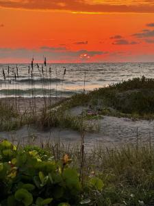 a sunset on the beach with people in the water at Unit 109 -1br Apt Oceanfront Complex With Pool in Cocoa Beach