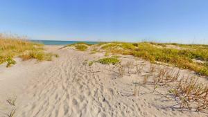 a sandy beach with grass and the ocean in the background at Unit 109 -1br Apt Oceanfront Complex With Pool in Cocoa Beach