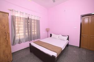 a bedroom with a bed with pink walls and a window at The Camp Club Beach Villa in Payyannūr