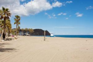 Una playa de arena con palmeras y el océano. en Apartamento céntrico Belquimar a pocos pasos de la playa, en Carboneras