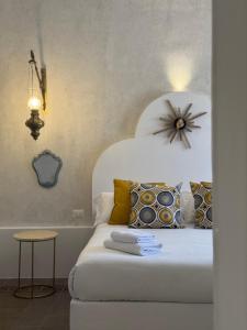 1 dormitorio con 1 cama blanca y reloj en la pared en I Lumi, en Catania