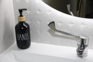a black bottle of soap sitting on a bathroom sink at Ruzafa Alegria in Valencia
