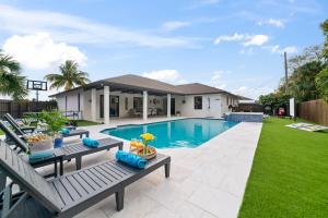 a backyard with a swimming pool and a house at West Palm Beach The Grand Luxe Villa-Heated Pool, Spa & Game Room in Lantana