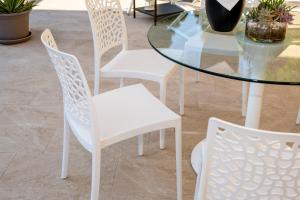 Terrace Apartment -M3 Apartments في ليدو دي يسولو: طاولة زجاجية مع كراسي بيضاء وطاولة زجاجية