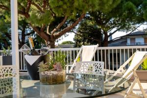 Terrace Apartment -M3 Apartments في ليدو دي يسولو: طاولة زجاجية وكراسي على شرفة مع شجرة