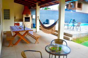a patio with a hammock and a table and chairs at Casa com piscina 500m da praia condomínio Morada da Praia in Bertioga
