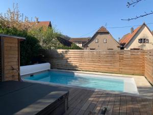 a swimming pool in front of a wooden fence at CHEZ SUZEL in Hunawihr