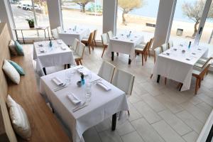 a restaurant with white tables and chairs with a view of the ocean at Rallye Hotel in L'Escala