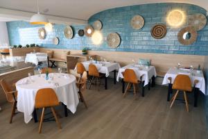 a restaurant with white tables and chairs and a blue wall at Rallye Hotel in L'Escala
