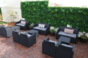 a patio with black wicker chairs and a hedge at Rallye Hotel in L'Escala
