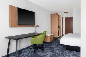 a room with a desk and a bed and a green chair at Fairfield Inn & Suites Jackson in Jackson
