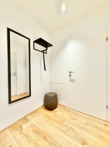 a mirror in a white room with a wooden floor at Apartment mit Balkon und Parkplatz in Vienna +1 photo