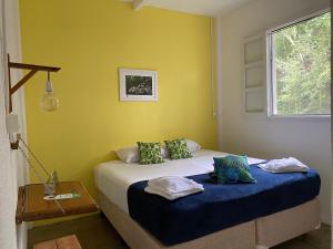 a bedroom with a bed and a yellow wall at Legado das Águas in Miracatu +9 photos