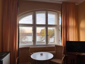 a room with a large window with a table and a tv at Villa am Peetzsee in Schlangenluch