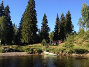 a boat on a river with a house in the background at Trysil Hyttegrend in Trysil +105 photos