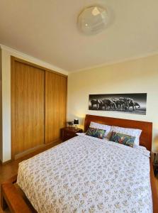 a bedroom with a large bed with wooden cabinets at A SELVA T2 in Caniço in Caniço