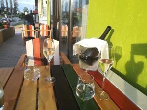 three glasses of wine sitting on a wooden table at Laura Apartament in Târgu-Mureş