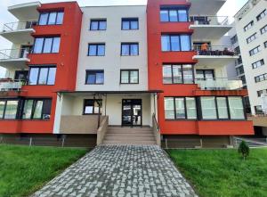 a red and white apartment building with a brick driveway at Laura Apartament in Târgu-Mureş