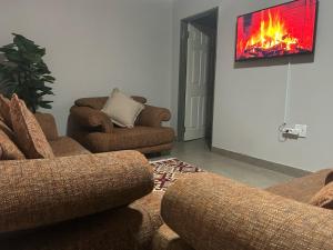a living room with two couches and a fire on the wall at Kufihliwe Lodge in Ingogo